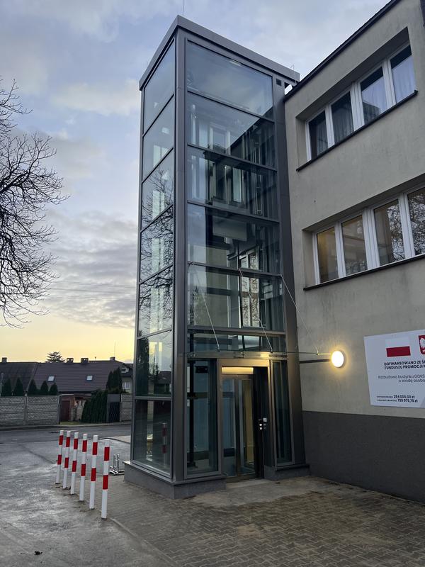 Przeszklony szyb windy osobowej przy budynku administracyjnym