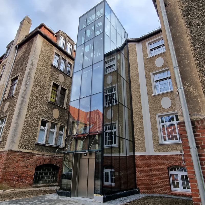 Przeszklony szyb windy szpitalnej dobudowany do zabytkowego budynku